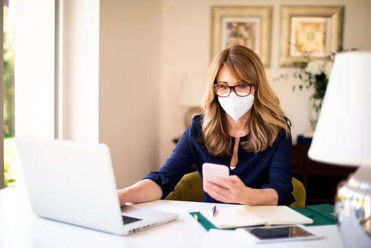 Mature Woman Wearing Face Mask While Working From Home During Coronavirus Pandemic
