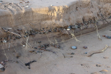 Pebbles in the sand layers along the sea shore