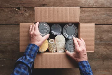 a person packing a donation box with food items © goodmanphoto