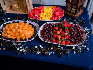 Assorted fruit trays with cantaloupe, strawberries, blackberries, watermelon, pineapple, and grapes.
