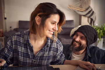 Young couple in the living room, girl working remotely because of the global pandemic.