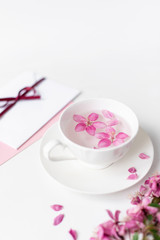 Spring background for the inscription, pink flowers, sakura cherry blossoms, letters, a cup with water and flower petals, top view, circle frame, copy space, flat lay 