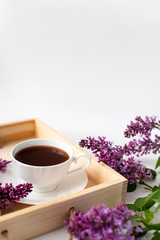 Obraz na płótnie Canvas Branches and flowers of lilac, violet color, on a white background. Cup with coffee, cocoa, spring breakfast. Creative flat lay, frame for text. Minimalistic design. Panoramic banner background with 
