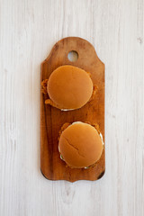 Homemade Burgers with fried chicken strips on a rustic wooden board on a white wooden surface, top view. Flat lay, overhead, from above.