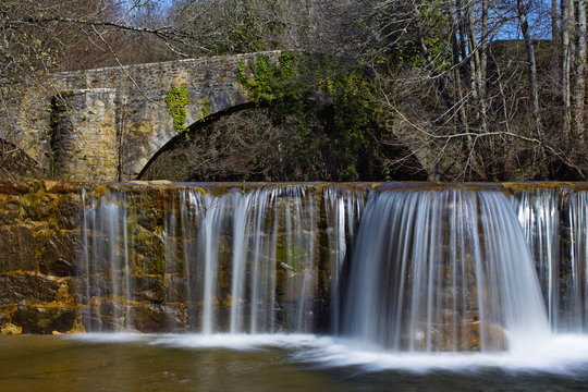 Sarria, Araba/Basque Country; Mar. 18, 2017. Dam and an old bridge over the Bayas river as it passes through Sarria in the Natural Park of Gorbeia.