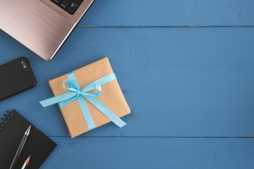 Fathers day, birthday and holiday concept. Gift box, laptop, smartphone and note pad on blue wooden...