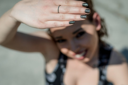 Sunlight hand protection. Young woman covering with hand's shadow the eyes to avoid sunlight. Focus on the hand.