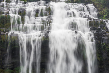 Flowing water of large and high waterfall on mountain cliff in the tropical rain forest. Beautiful nature waterfall in Bolaven Plateau, southern Laos, Tad kamud waterfall