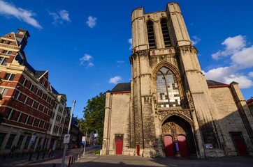 Fototapeta na wymiar Ghent, Belgium, August 2019. In the heart of the historic center, the church of St. Michael. The warm light of the late summer afternoon enhances the massive facade. On the left the homonymous bridge.