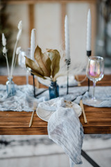Wedding banquet. Festive decoration in bright colors. Wooden table served with cutlery, candles, dried flowers and linen sky blue runner