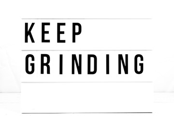 Inspirational Keep Grinding quote on vintage retro board. Concept. flat lay