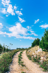 Fototapeta na wymiar Mountain path. Hiking trail with beautiful bright sky. Active lifestyle concept. Road trip with seascape view over Adriatic coast. Active vacation concept. Background with copy space.Adventure time.