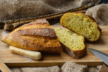 Bread with salt on a wooden board with a knife on a black background.