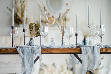 Autumn table decoration, wooden table served with dried flower, white plate, vintage cutlery, candeles with bright blue gauze tablecloth. Top view, selective focus.