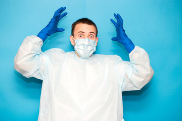 Portrait of scared man in protective suitt, medical mask and gloves against viruses and infections isolated on blue