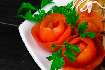 fishballs and meatballs with eggplant rolls with cottage cheese and tomato, parsley on a white plate on a black background