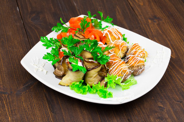 fishballs and meatballs with eggplant rolls with cottage cheese and tomato, parsley on a white plate on a black background