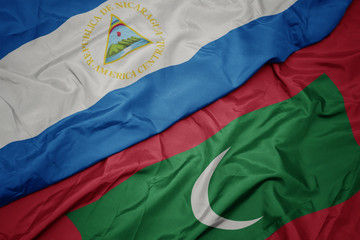 waving colorful flag of maldives and national flag of nicaragua.