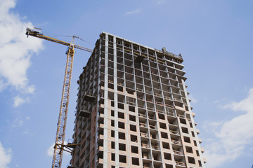 Fototapeta na wymiar Construction of a multi-storey residential building. Construction crane. Against the blue sky
