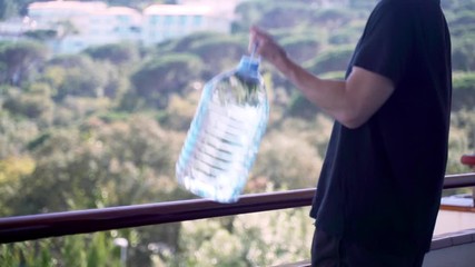 Sport at home. Workout at home. Man doing exercises using plastic bottle of water like a kettlebell. Hand exercises. Sport with improvised tools. Stay home. Keep fit during quarantine. Biceps,triceps 