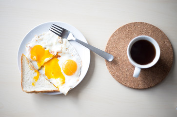Two fried eggs with orange yolks, white toast and black espresso coffee in the morning for breakfast.