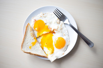 Two fried eggs with orange yolks, white toast in the morning for breakfast.