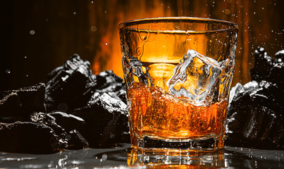 ice falls into a glass with expensive whiskey and spray flies in different directions
