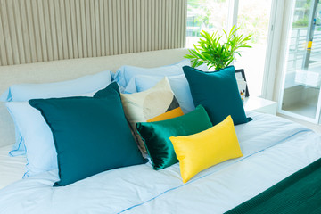 Yellow and green pillow on bed in modern interior bedroom.