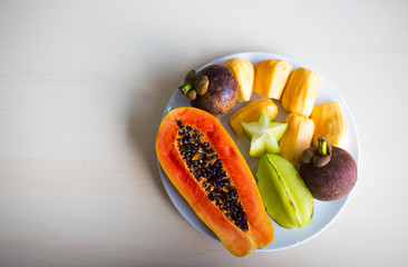 Bowl of delicious tropical fruit salad on wooden background. Top view.
