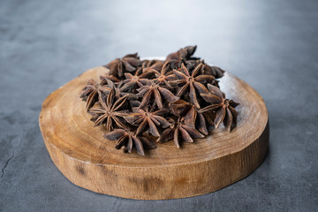 Anise stars in wooden serving board on stone, concrete background. 