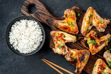 Grilled chicken wings in barbecue sauce and rice in a bowl on a concrete background