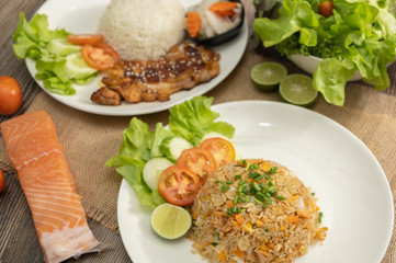 Fried rice with egg and grilled salmon, foreground with chicken teriyaki rice on the wooden table -Stock photo