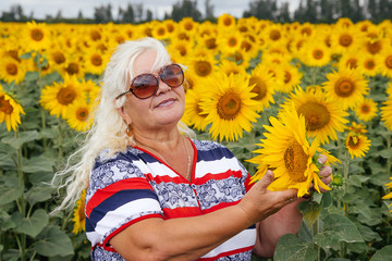 Portrait of an elderly woman in a field of sunflowers.