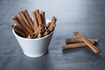 Cinnamon sticks in white porcelain bowl.