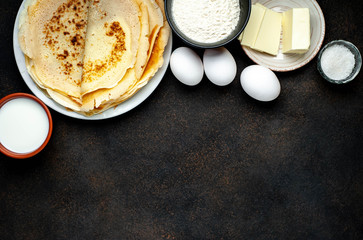 Recipe for making thin home-made pancakes. Ready-made thin pancakes, flour, eggs, butter, milk, sugar on a stone background with copy space for your text.
