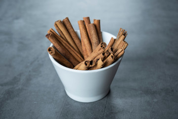 Cinnamon sticks in white porcelain bowl.