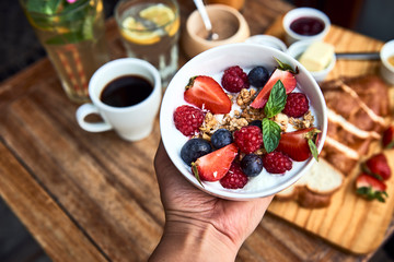 Hand holding plate with joghurt with fruits