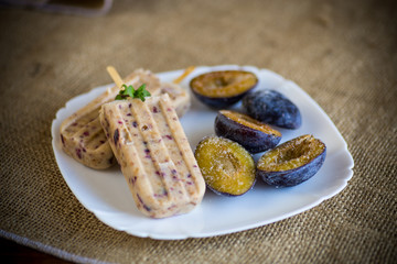 plum sweet homemade ice cream on a stick with slices of plum inside, in a plate