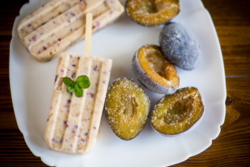 plum sweet homemade ice cream on a stick with slices of plum inside, in a plate