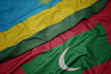 waving colorful flag of maldives and national flag of rwanda.