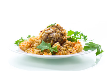 boiled bulgur groats with vegetables and meatballs in a plate