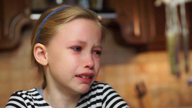 Blond beautiful child girl in striped dress crying badly tears drop down her face offended at home. Saying no. Child abuse or bad childhood