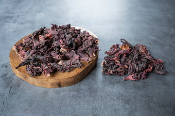 Hibiscus tea in wooden serving board on stone, concrete background. Dry, organic, healthy and relaxing herbals.
