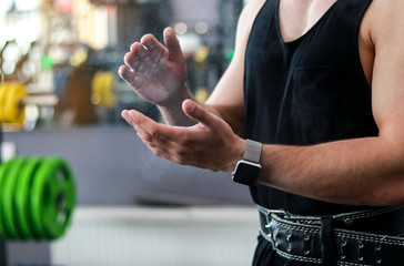 a young man before training rubs magnesia on his hands and claps his hands