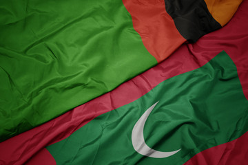waving colorful flag of maldives and national flag of zambia.