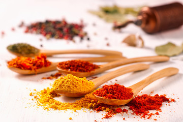 Closeup of bright spices pepper, paprika, saffron, mint in wooden spoons