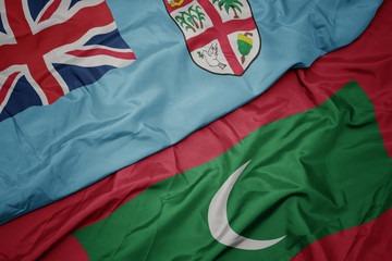 waving colorful flag of maldives and national flag of Fiji .