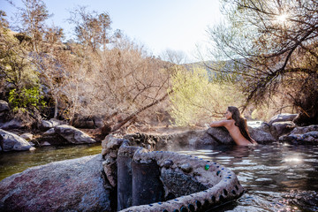 Woman in a natural hot spring by a river