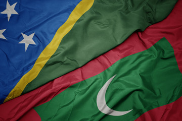 waving colorful flag of maldives and national flag of Solomon Islands .