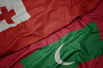 waving colorful flag of maldives and national flag of Tonga .